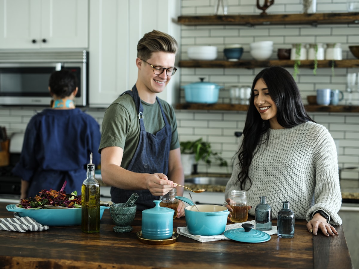 Two people talking and laughing while cooking together at a kitchen counter
