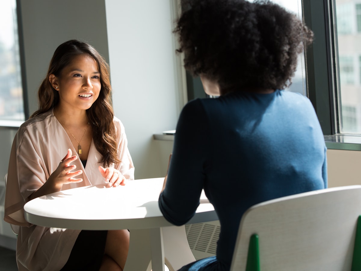 Two people in calm conversation across a table in soft natural light